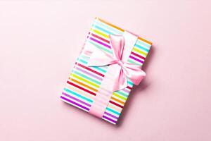 Gift box with pink bow for Christmas or New Year day on pink background, top view with copy space photo