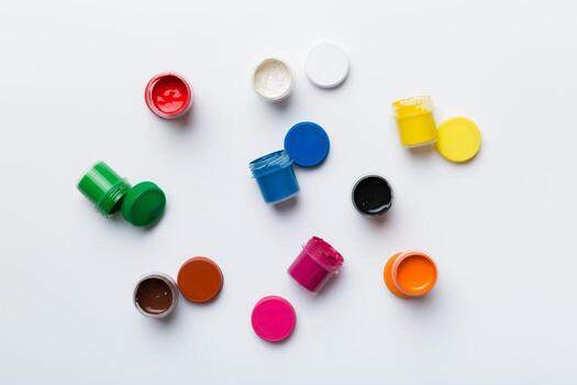 jars with gouache of different colors on Colored background. hobby painting. Top view with empty space. workplace for creativity. home teaching concept drawing photo