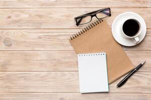 Modern office desk table with notebook and other supplies with cup of coffee. Blank notebook page for you design. Top view, flat lay photo