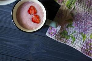 Strawberry dessert. A mug with strawberry creamy fresh, bowl with ripe strawberries and lupine on a dark blue wooden table. Beautiful food still life. photo