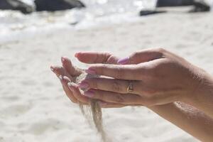 The sand is pouring from woman's hands. photo