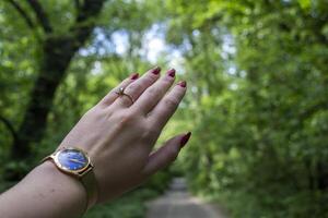 Female hand with red manicure points summer path. photo