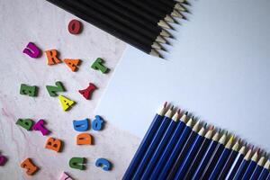 Multicolor letters and set of pencils on the table. Colorful wooden alphabet and pencils on a table. photo