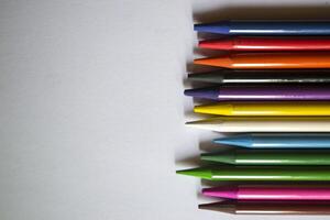 Multicolored pencils on white background. A palette of pencils on a table, close up. photo