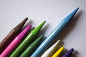 Multicolored pencils on white background. A palette of pencils on a table, close up. photo