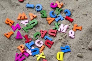 Multicolor wooden letters on a sand close up. photo