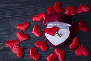 Engagement ring in a red box on a love hearts background. photo