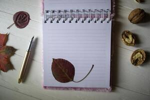 un abrió cuaderno y bolígrafo en un escritorio con decoración por caído hojas. atmosférico otoño antecedentes con Copiar espacio. foto