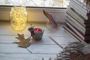 Cozy desktop with books, candle light and beautiful decorations. photo