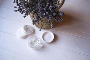 A jar with skin cream and lavender flowers on a white wooden background. photo