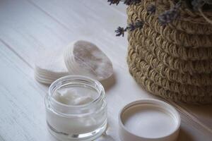 A jar with skin cream and lavender flowers on a white wooden background. photo