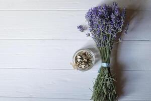 Bouquet of lavender and wooden love hearts in a jar, on a white wooden table. Beautiful romantic background with copy space. photo