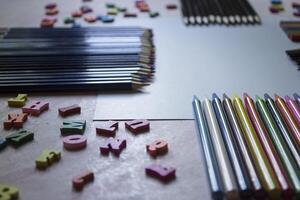 multicolor letras y conjunto de lapices en el mesa. vistoso de madera alfabeto y lapices en un mesa. foto