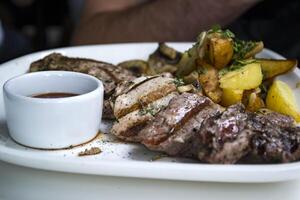 The meat and fried potatoes with sauce on the white plate. photo