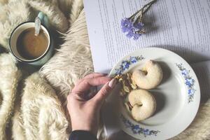 Coffee, cake and book. Woman holding a nut. Cozy atmosphere of home. photo