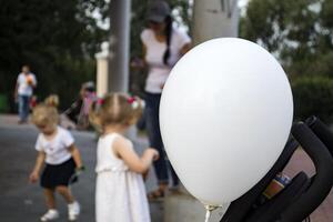 White balloon close-up and children playing in the background. photo