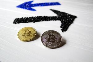 Golden and silver bitcoins with arrows up and down on a white wooden background. photo