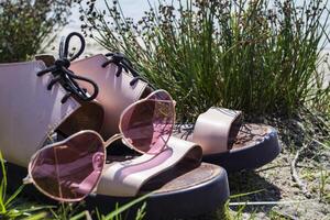 Female shoes and pink glasses on the coast of blue lake. photo