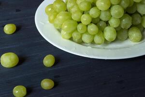 Ripe grapes in a plate on a dark blue wooden table. photo