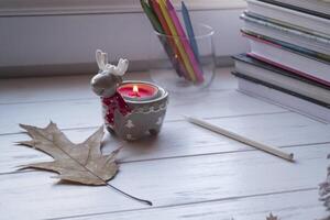 Cozy desktop with books, candle light and beautiful decorations. photo