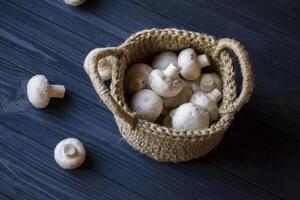 The champignons in a basket on a wooden table. photo