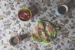 el emparedados con salmón, frutas y bebidas en un cocina mesa. sabroso desayuno. foto
