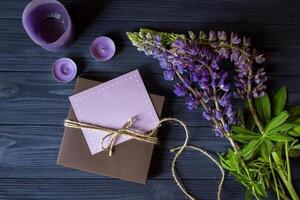 regalo caja con saludo tarjeta y ramo de flores de altramuces en un oscuro azul de madera antecedentes. foto