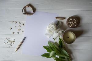 White paper, pen, peony and decor on the desk. Beautiful still life on the desktop. photo