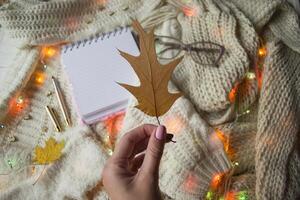 Girl holding autumn leaf. Cozy flat lay. photo