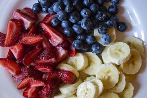 Plate with bananas, strawberries and blueberries. photo