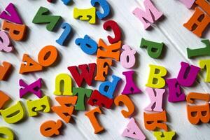 Multicolor letters on a white wooden background. Colorful wooden alphabet on a table. photo