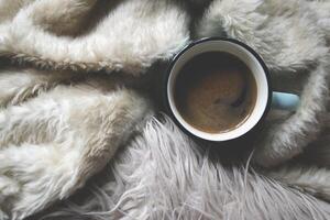 A mug of coffee on a warm plaid. Cozy atmosphere of home. photo