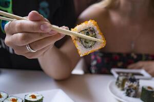 mujer es participación Sushi rodar en bambú palos foto