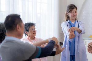 Portrait of elderly smiling Asian woman and people aerobics in nursery house. Seniors are moving their body arms and shoulders for a healthy life. retired people activities group concept. photo