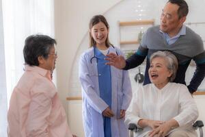 Asian young nurse support couple senior older man and woman in a wheelchair. elderly mature and a group of senior friends living in the hospital. socializing of retired people. photo