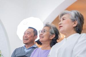 cerca arriba mayor hembras y masculino sentado en banco. más viejo personas son escuchando y disfrutar reunión atención grupo a vivo habitación. alegre despreocupado retirado mayor amigos disfrutando relajación a por poco hogar. foto