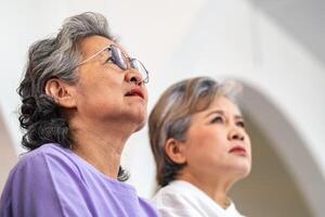 close up senior females and male sitting on bench. older people are listening and enjoy meeting focus group at living room. Joyful carefree retired senior friends enjoying relaxation at nearly home. photo