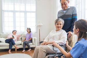 Asian young nurse support couple senior older man and woman in a wheelchair. elderly mature and a group of senior friends living in the hospital. socializing of retired people. photo