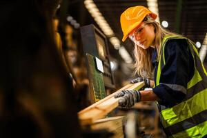 fábrica ingeniero mujer en pie confidente a controlar panel cambiar. trabajador trabajos a pesado máquina a industria fábrica. trabajador comprobación madera de crudo madera material. inteligente industria trabajador operando. foto