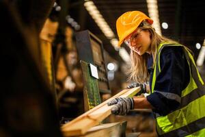 Factory engineer woman standing confident to control panel switch. Worker works at heavy machine at industry factory. worker checking timber of raw wood material. smart industry worker operating. photo