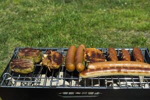 el salchichas y carne en parrilla. verano picnic exterior. foto