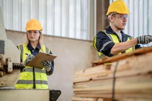 worker carpenters working in machines to cut wood timber. man and woman are crafting with wood in a workshop. two craftsmen or handymen working with carpenter tools or electric machines. photo