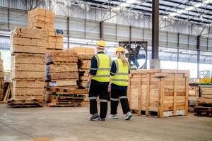 workers man and woman engineering walking and inspecting with working suite dress and hand glove in the front machine. Concept of smart industry worker operating. Wood factories produce wood palate. photo