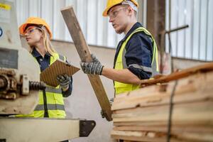 worker carpenters working in machines to cut wood timber. man and woman are crafting with wood in a workshop. two craftsmen or handymen working with carpenter tools or electric machines. photo