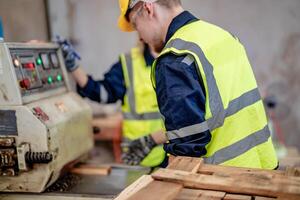 worker carpenters working in machines to cut wood timber. man and woman are crafting with wood in a workshop. two craftsmen or handymen working with carpenter tools or electric machines. photo