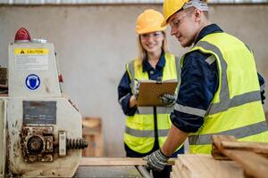 worker carpenters working in machines to cut wood timber. man and woman are crafting with wood in a workshop. two craftsmen or handymen working with carpenter tools or electric machines. photo