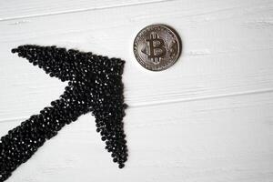 Silver bitcoin with black arrow up on a white wooden background. photo