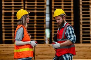 trabajadores carpintero vistiendo la seguridad uniforme y difícil sombrero trabajando y comprobación el calidad de de madera productos a taller fabricación. hombre y mujer trabajadores madera en oscuro almacén industria. foto