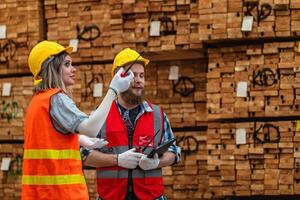 workers carpenter wearing safety uniform and hard hat working and checking the quality of wooden products at workshop manufacturing. man and woman workers wood in dark warehouse industry. photo