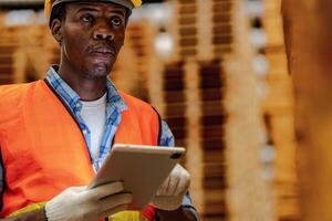 African worker carpenter wearing safety uniform and hard hat working and checking the quality of wooden products at workshop manufacturing. man and woman workers wood in dark warehouse industry. photo